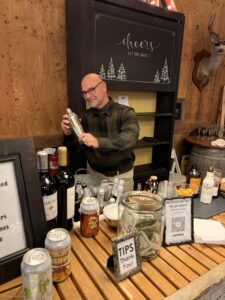 George, owner at Rein Fire Ranch, preparing a cocktail at the barn bar for a guest off screen